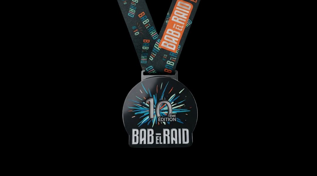 Médaille finisher Bab el Raid 2026 en métal noir avec visuel coloré pour la 10e édition du raid aventure dans le désert.