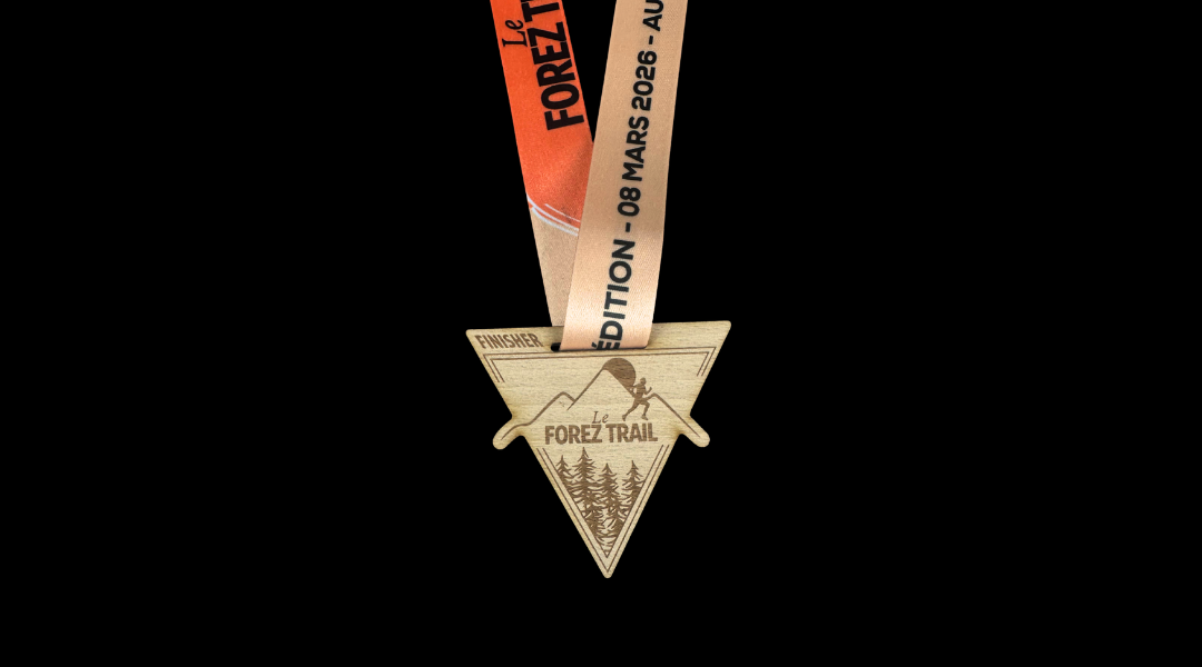 Médaille finisher en bois gravé en forme triangulaire pour Le Forez Trail 2026 avec ruban orange et beige personnalisé.